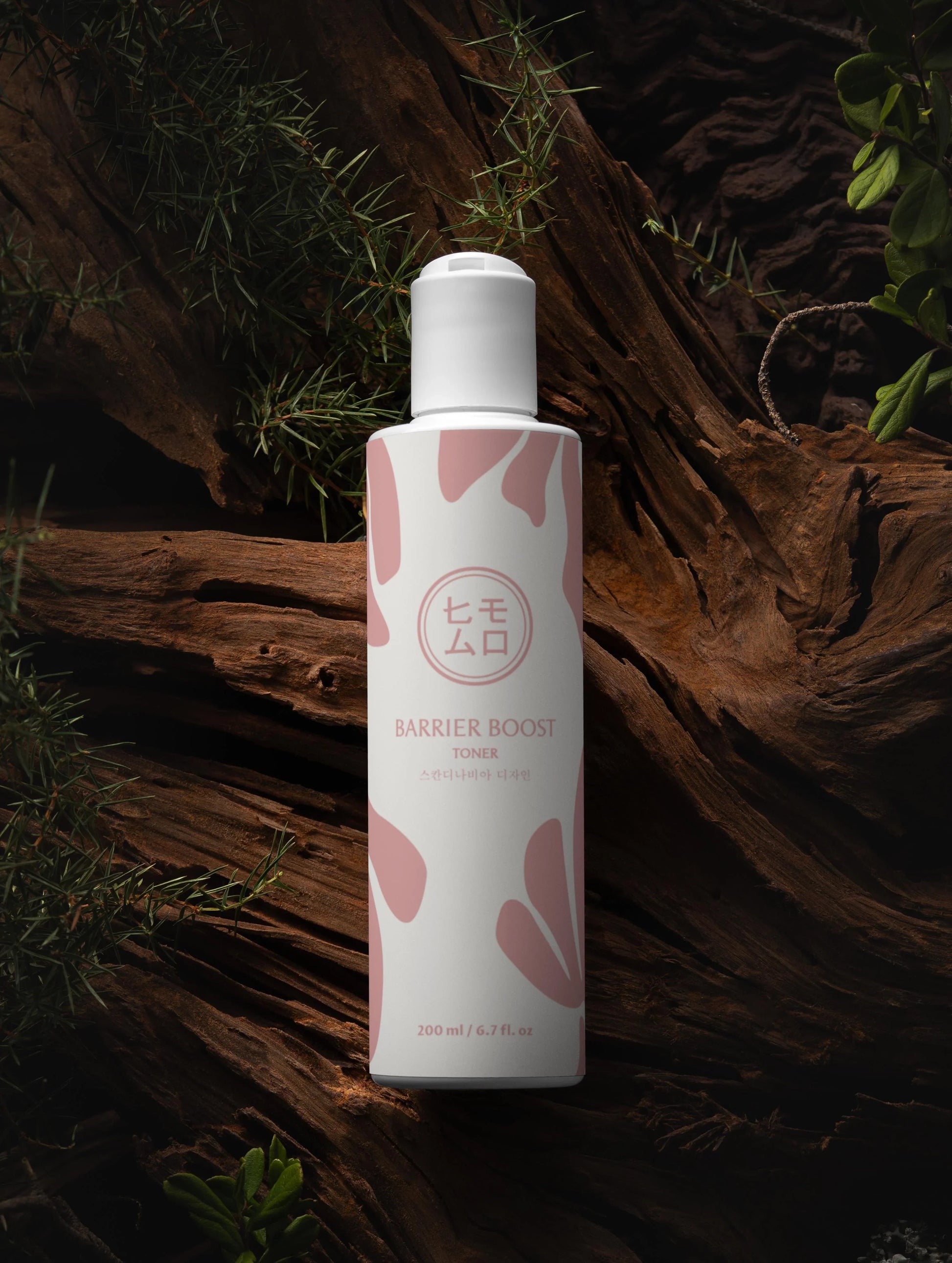 Barrier Boost tonerflaska med rosa mönster står på trä omgiven av grönska, hudvård K-beauty.